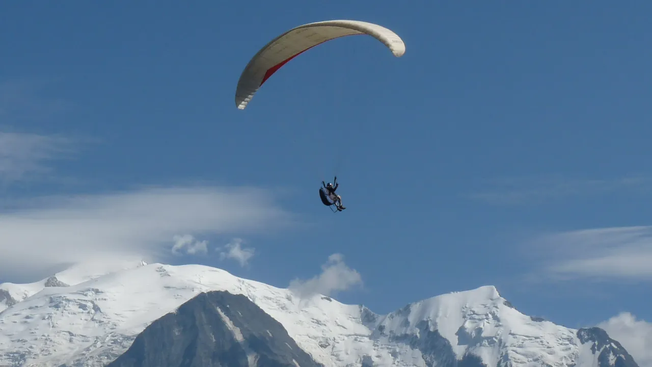Parapendio in volo davanti al massiccio del Monte Bianco